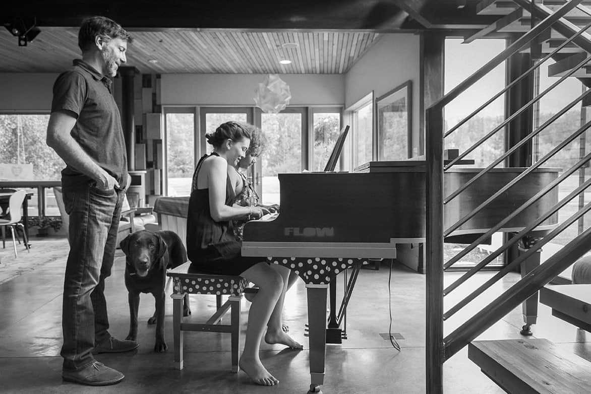 Alex watches his daughter's raucous rendition Chopsticks on the family piano nudging them to go faster with each round. From left to right: Alex, Woody the dog, Anna, and Layla. 